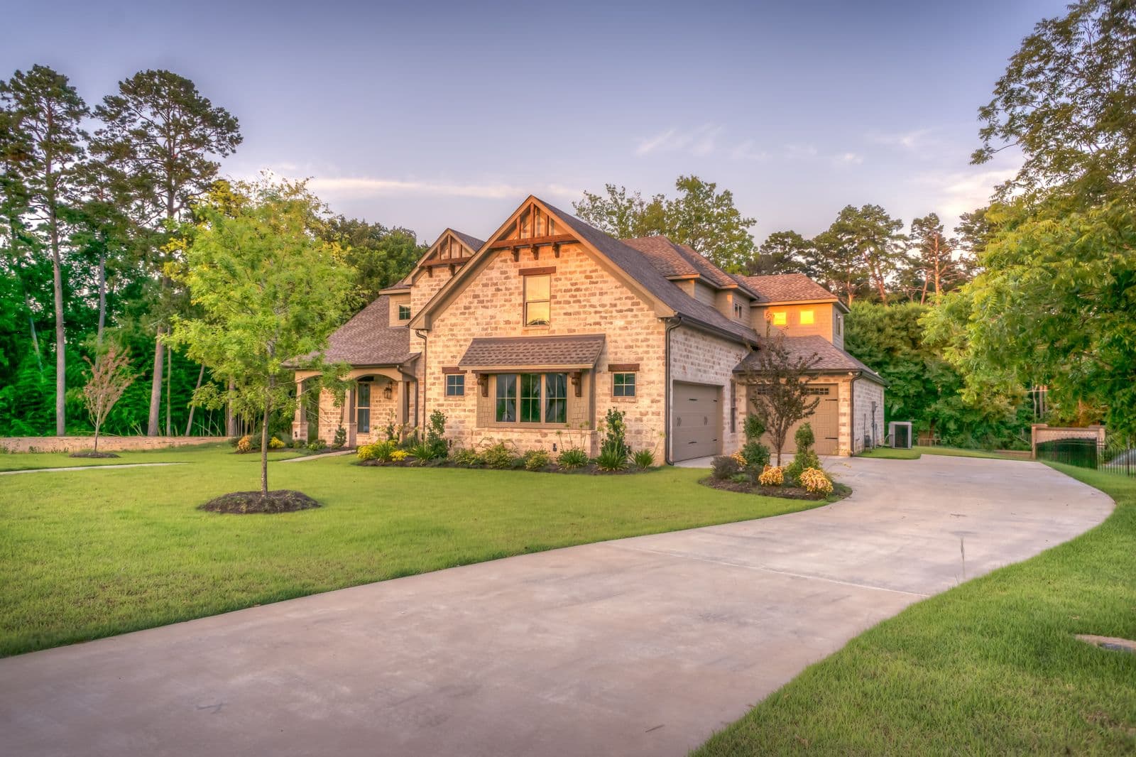 A brick family home with a curved driveway at dusk
