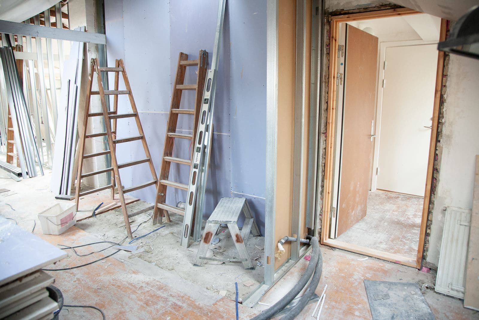 The inside of a house mid-renovation with ladders and bare drywall