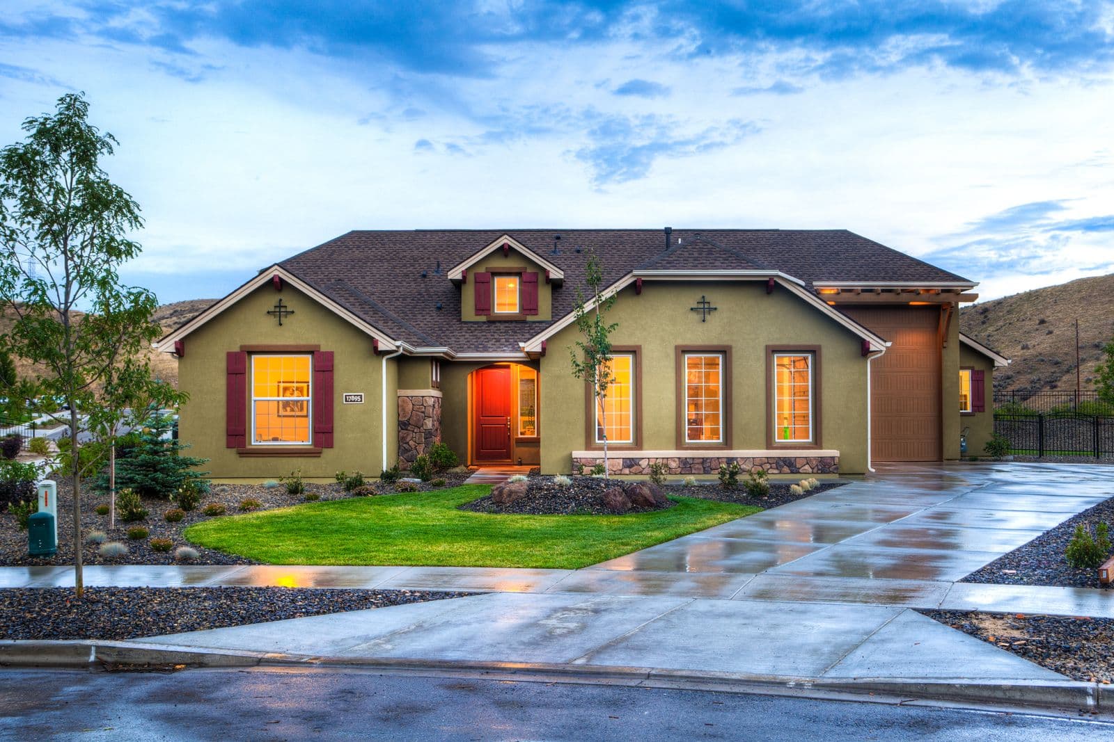 A house at dusk with an empty wet driveway and no cars